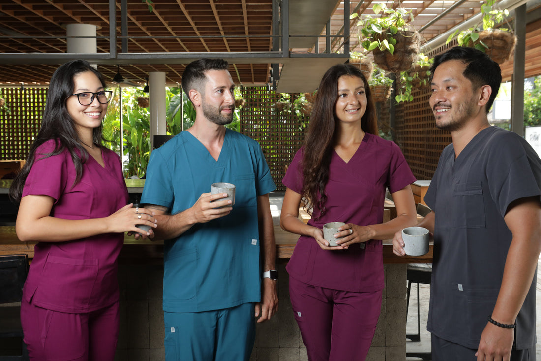 cuatro profesionales de la salud usando un uniforme clínico en los colores: gris, turquesa y burdeo