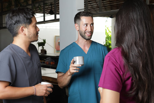 profesionales conversando y usando uniformes clínicos en color gris, tirquesa y burdeo