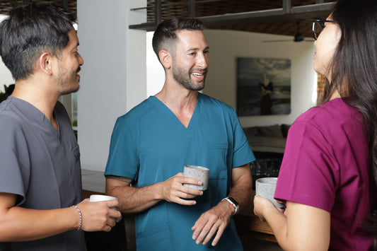 profesionales usando un uniforme clínico burdeo, un uniformes clínico gris y un uniformes clínico turquesa