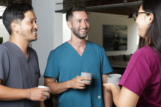 Profesionales usando uniforme clínico turquesa, gris y burdeo