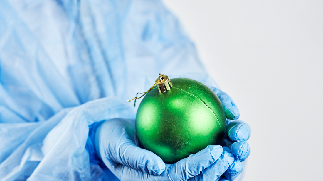 profesional de la salud sosteniendo una esfera de navidad usando uniformes clínicos